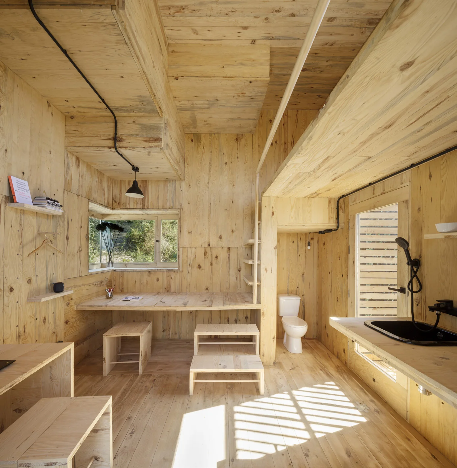 Interior of The Voxel cabin with exposed cross-laminated pine walls and built-in timber seating