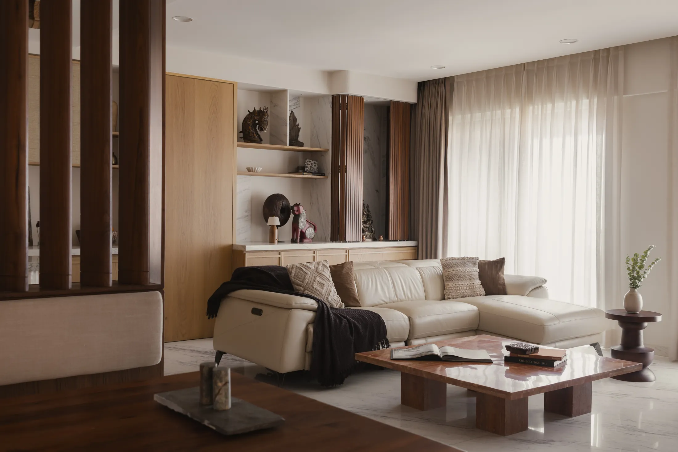 home in•between living room with a cream sectional sofa, low timber coffee table and sheer curtains