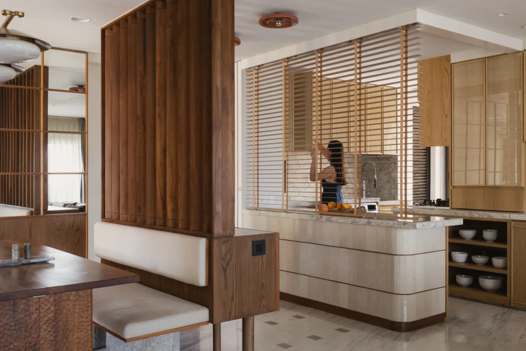 Concealed blinds lowered above the kitchen island to separate cooking and dining in home in•between