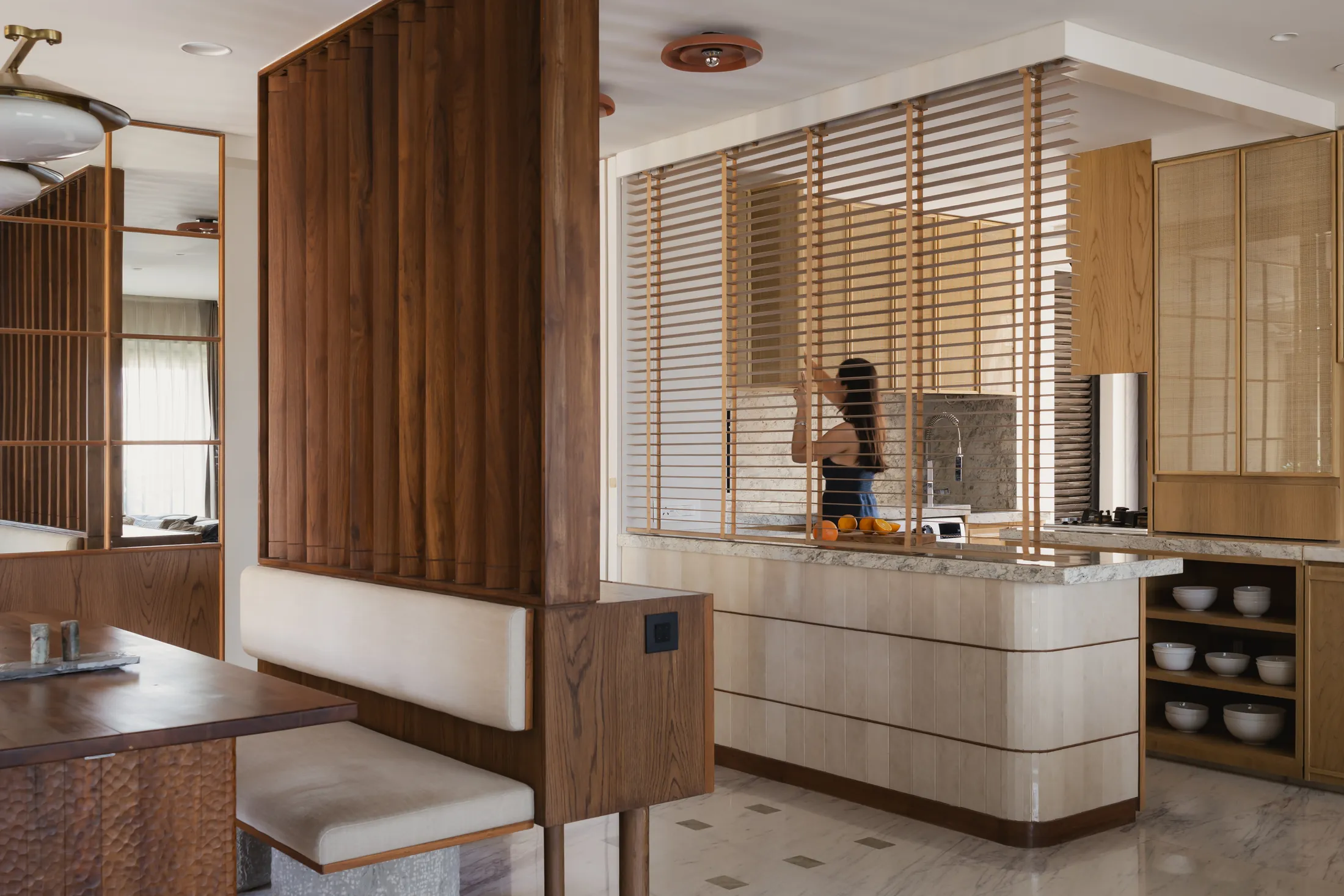 Concealed blinds lowered above the kitchen island to separate cooking and dining in home in•between
