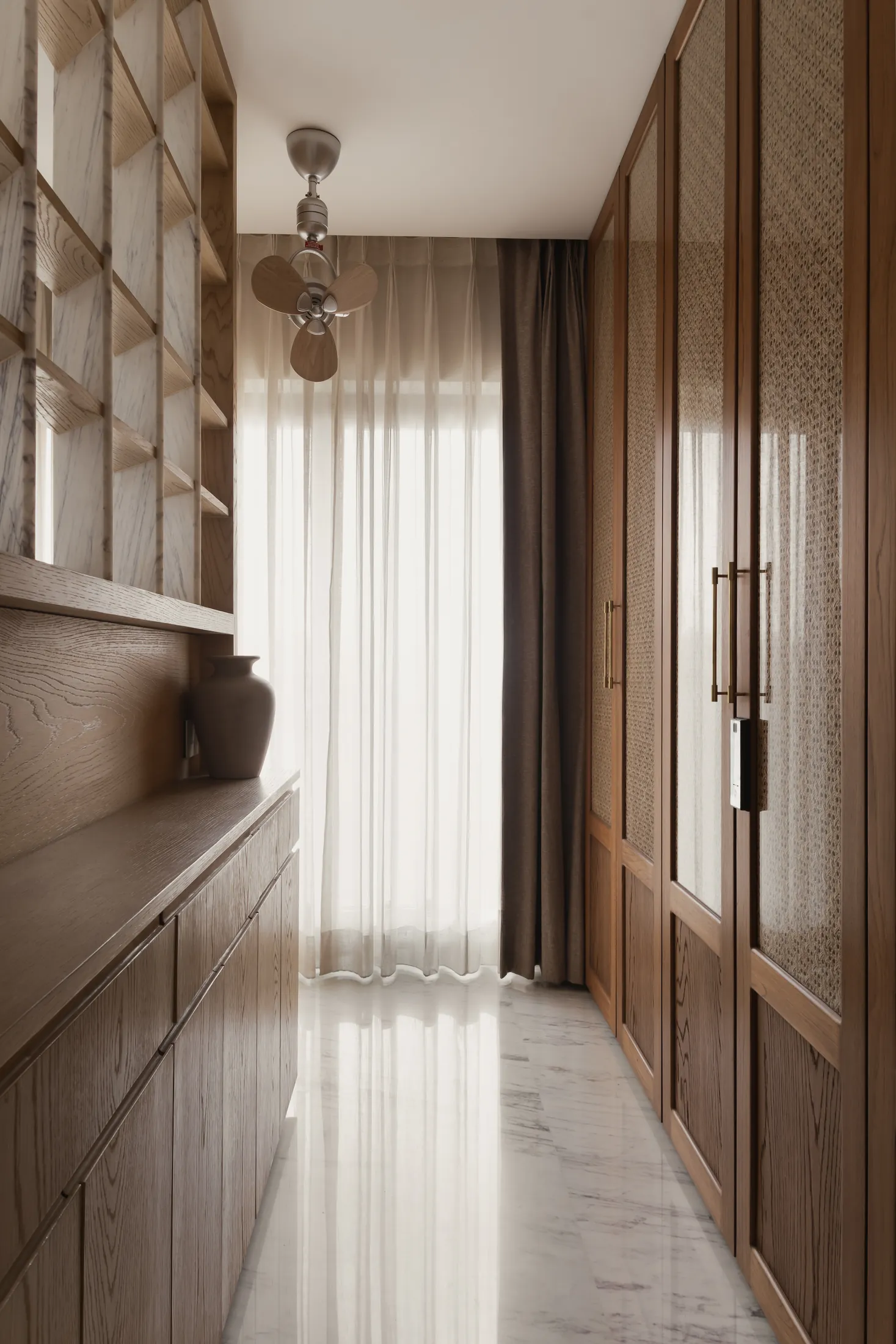 home in•between dressing passage lined with full-height teak wardrobes, with sheer curtains at the end
