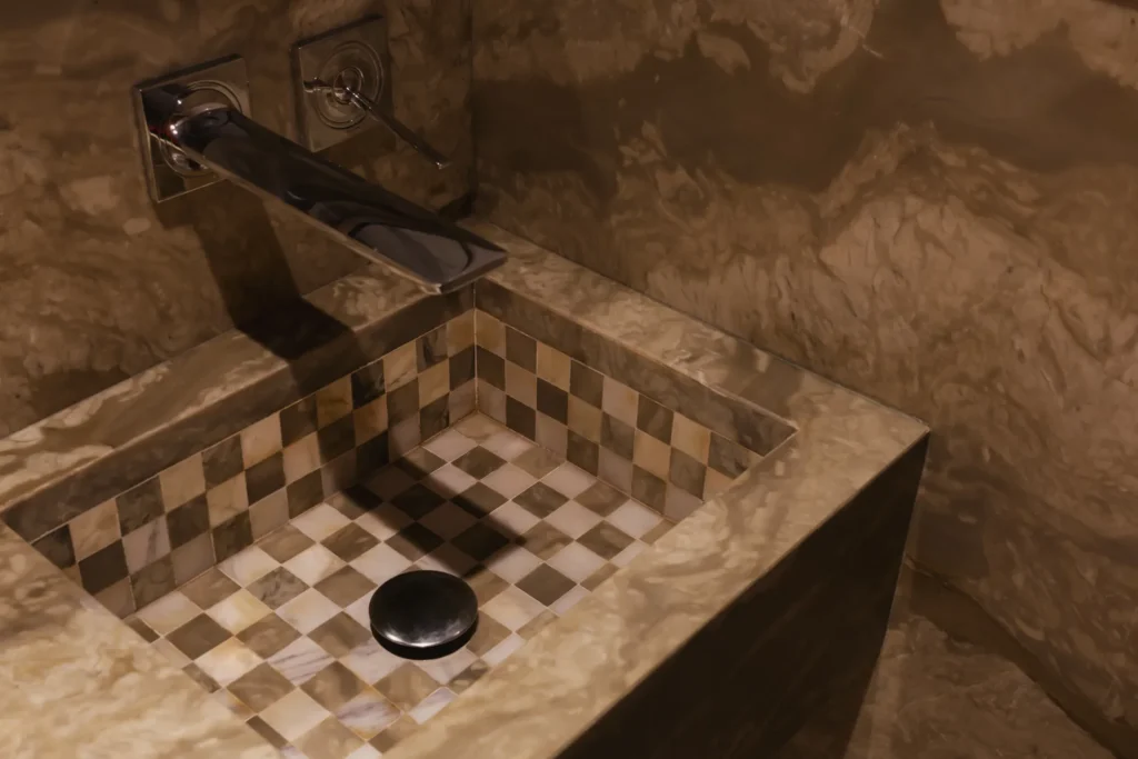 Basin lined with a checkerboard mosaic made from waste marble offcuts in the home in•between powder room