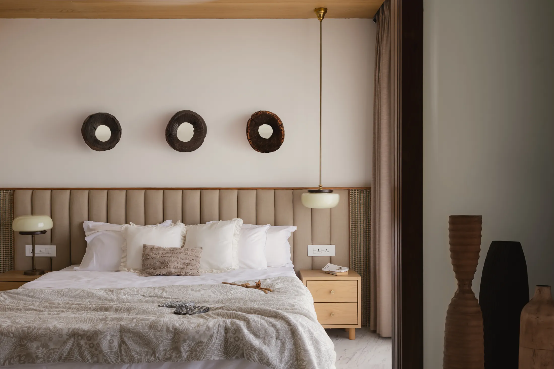 home in•between bedroom with a channel-tufted headboard, three round timber wall pieces and side tables