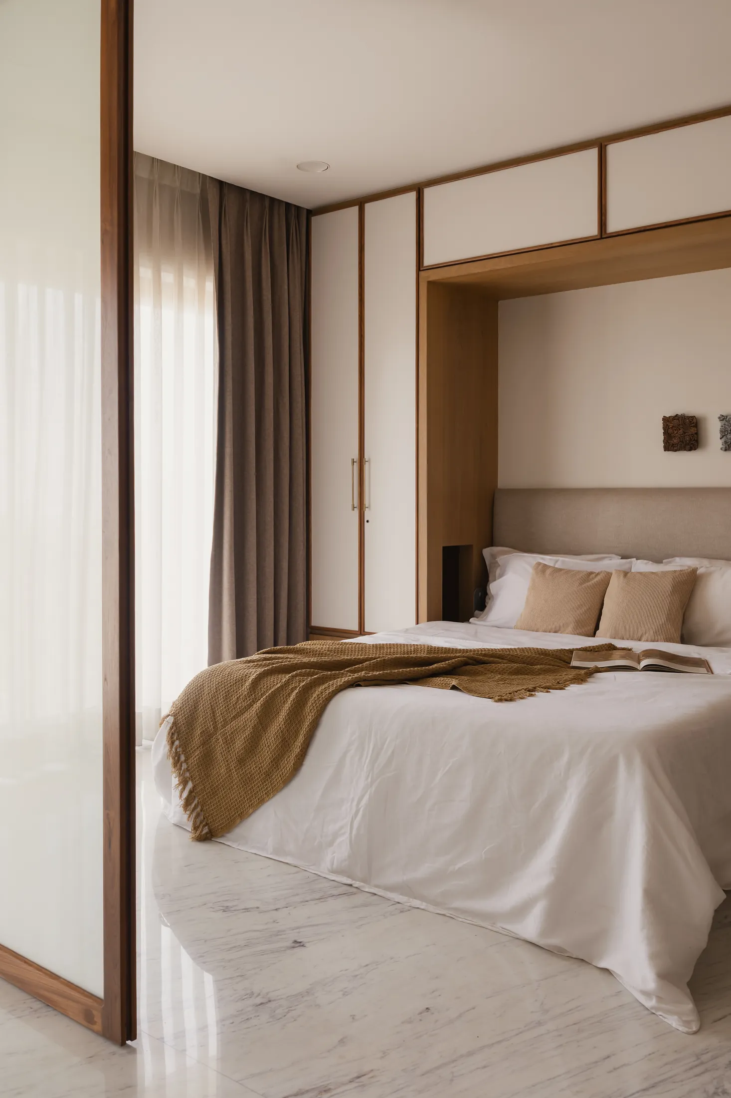 home in•between guest bedroom with the bed set in an alcove framed by white and timber wardrobes