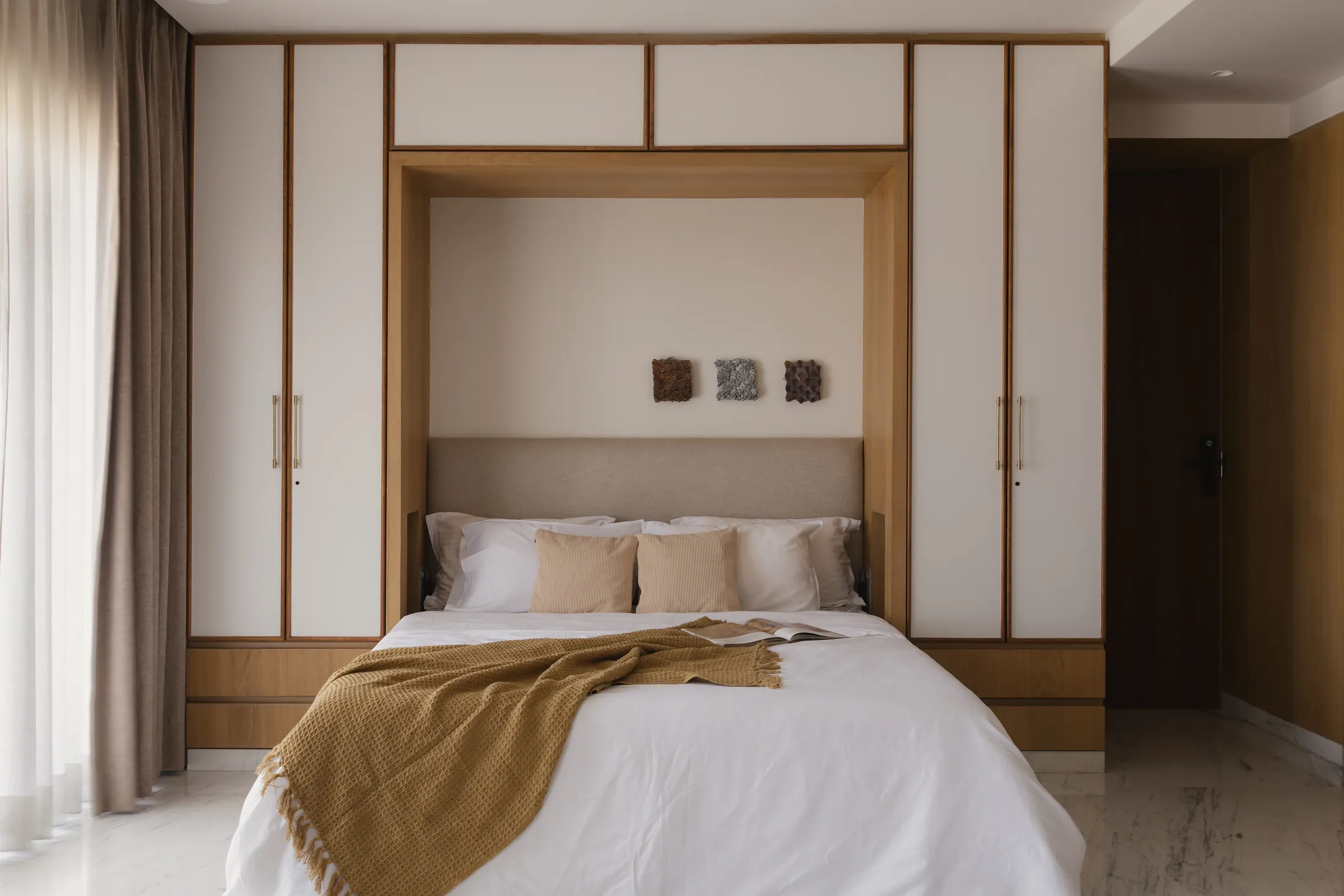 home in•between bedroom with a fold-away bed set into a wall of white and timber wardrobes