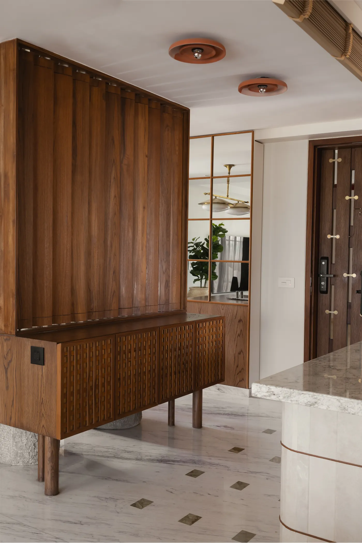 Solid teak louvre screen and sideboard at the entrance of home in•between, a Powai apartment by studio in•elements
