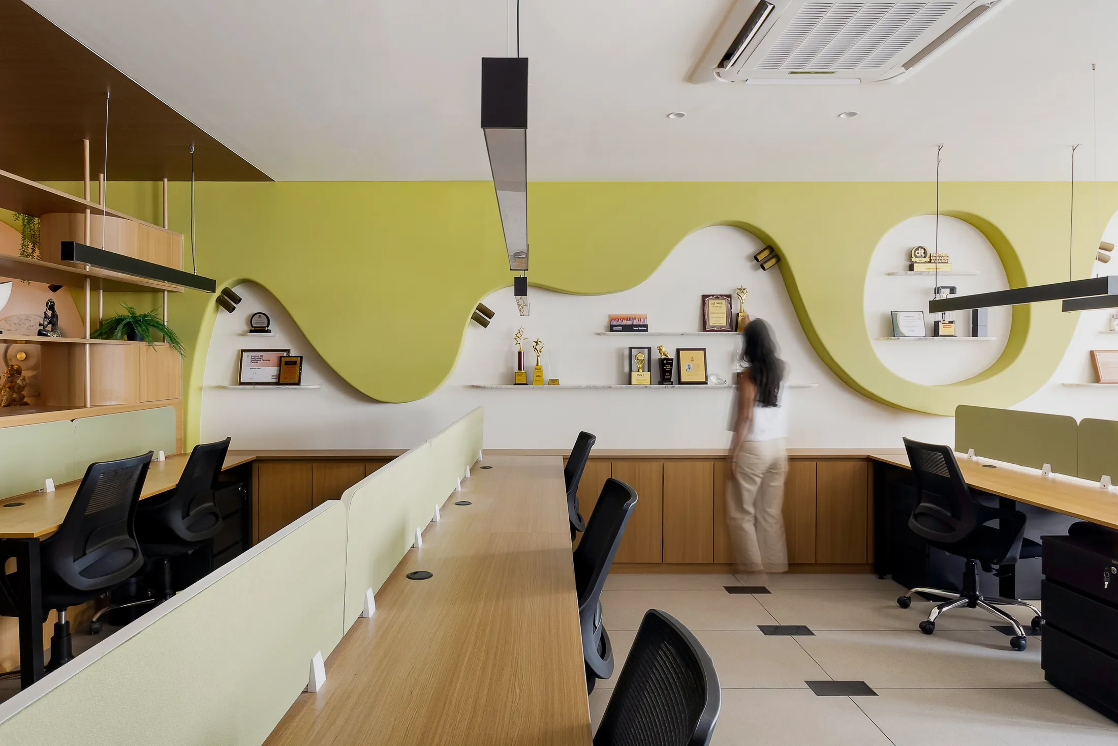 Into the Bend open office with long desks facing a wavy lime-green wall with circular display niches