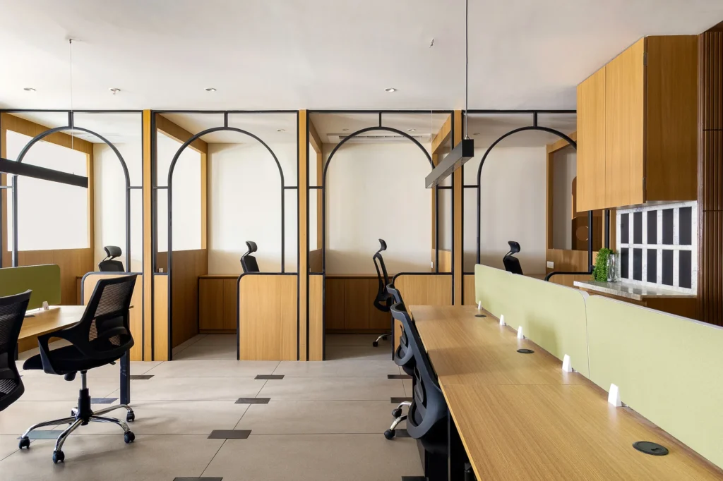 Arched black metal frames enclosing the private cabins beside the open workstations at Into the Bend