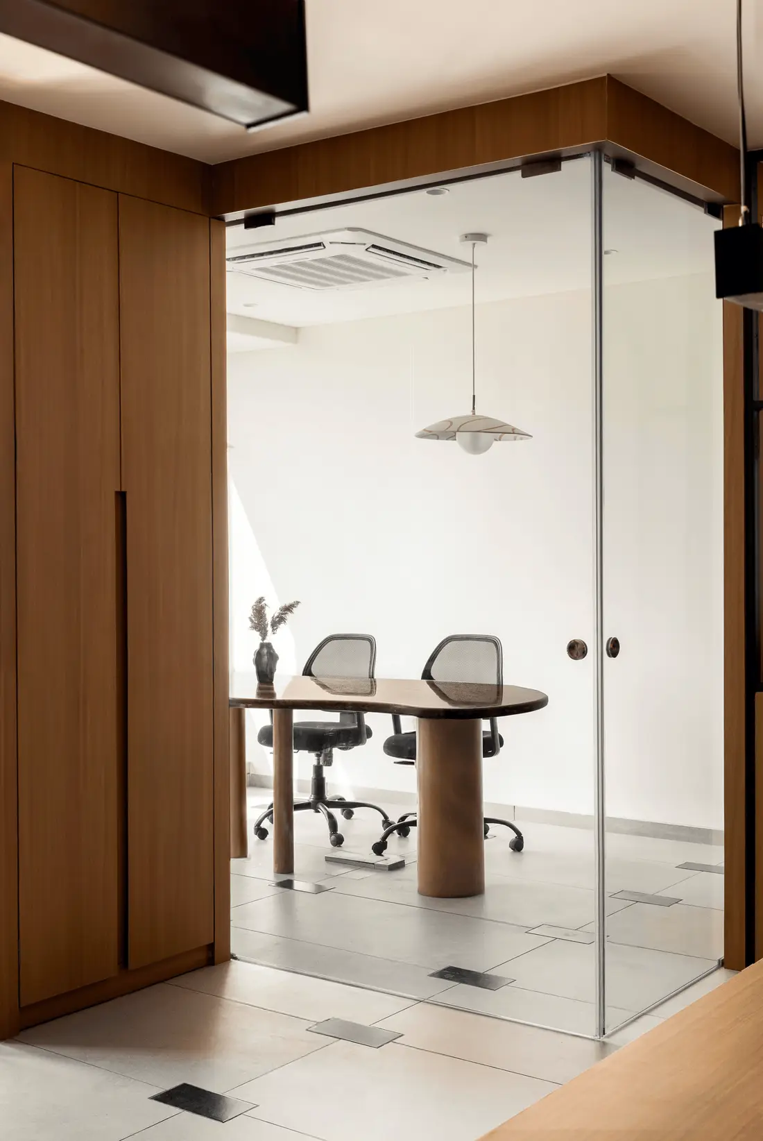 Into the Bend glass-walled meeting room with a round table, chairs and a pendant light