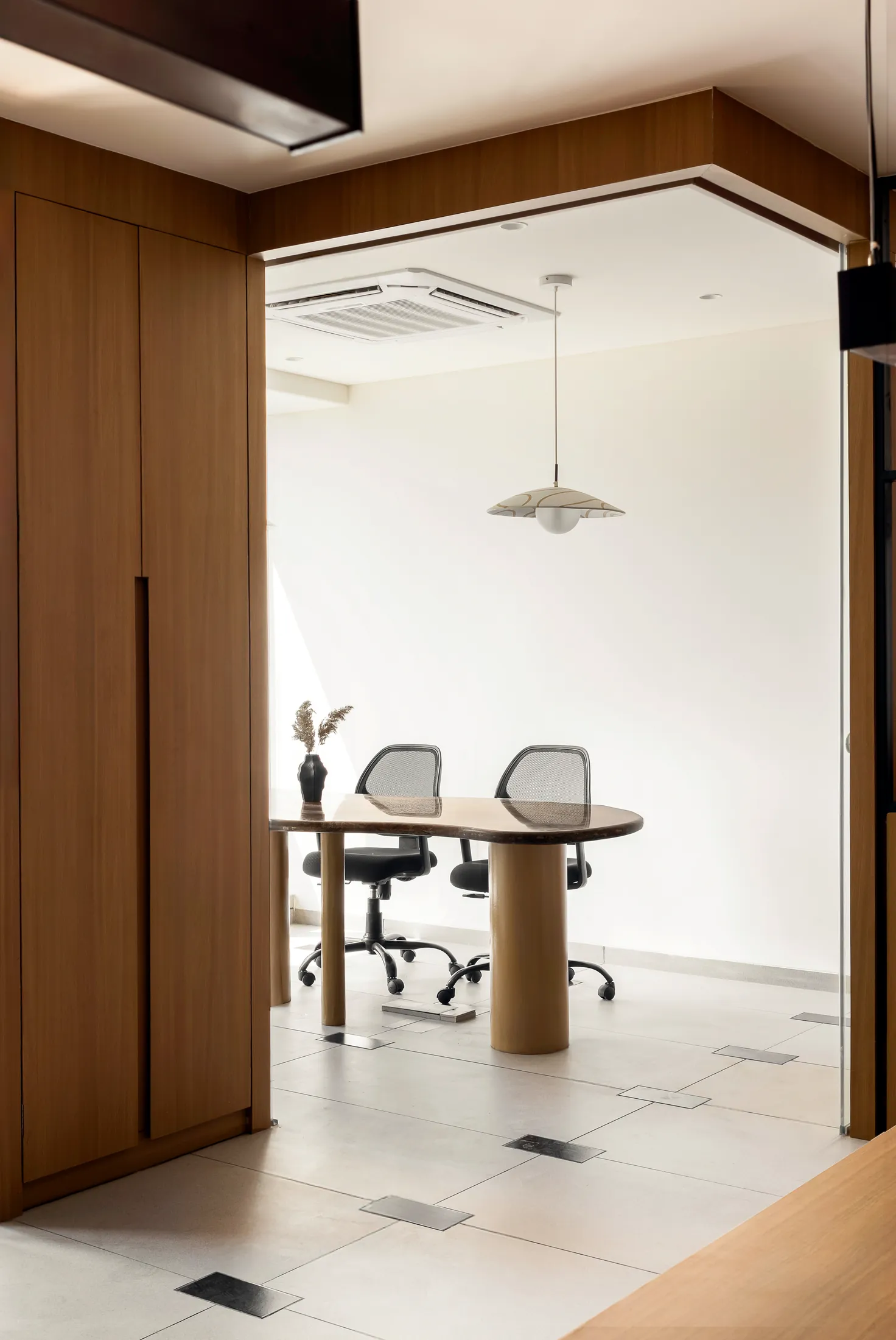 Conference room seen through frameless glass beside full-height oak laminate storage at Into the Bend
