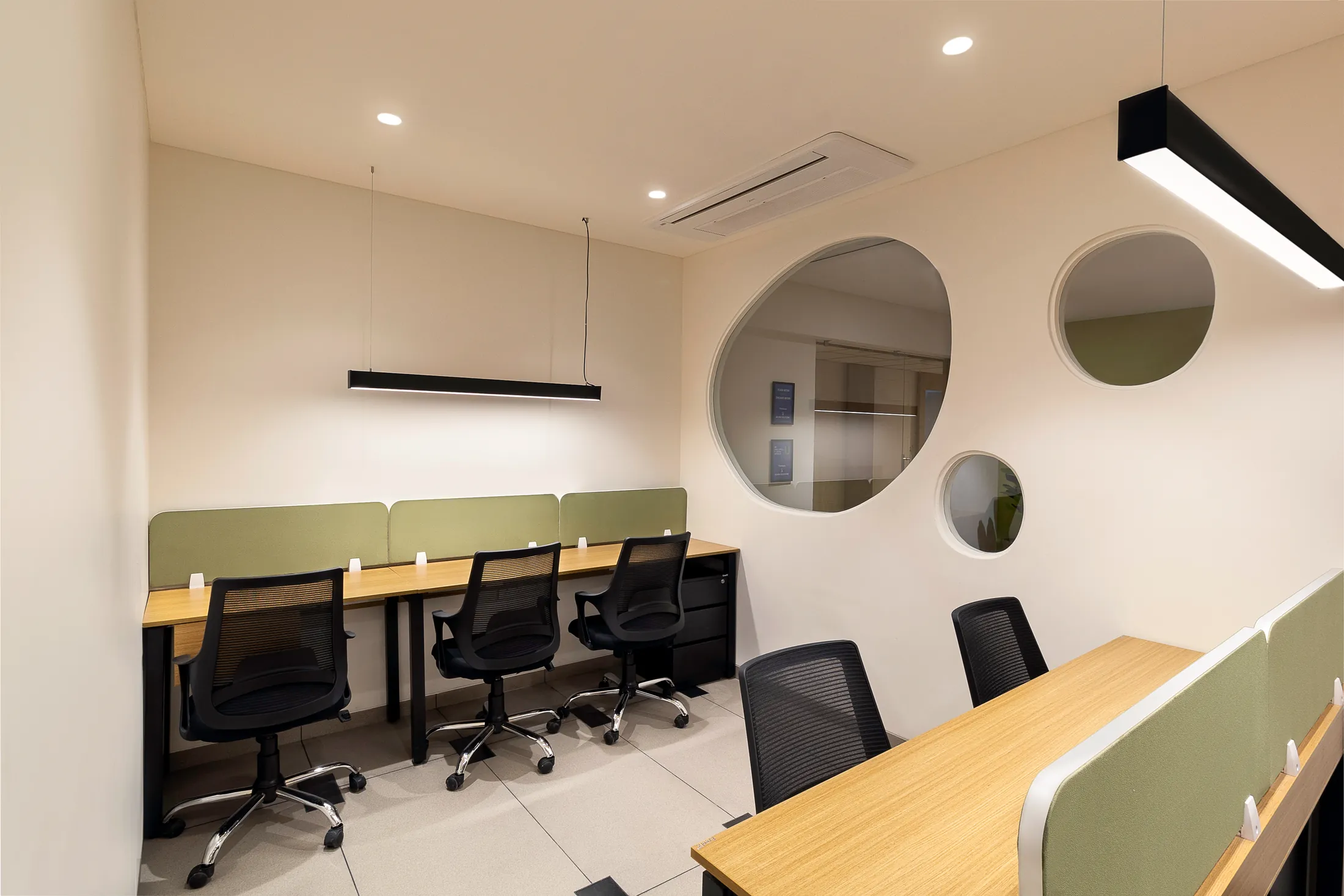 Into the Bend workstations with green pinboards, linear lights and round cut-outs in the wall