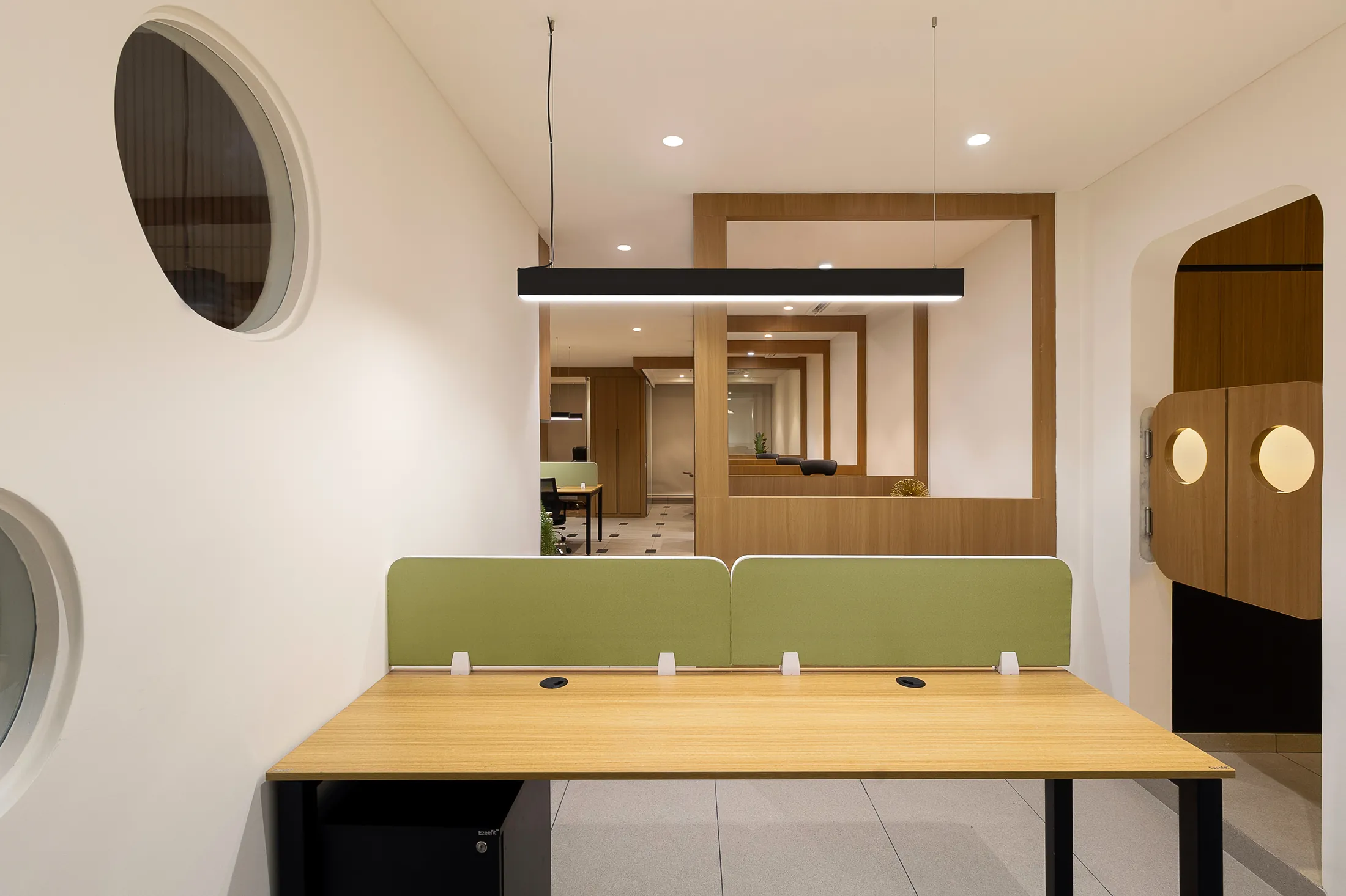 Into the Bend workstation zone with green desk panels, round mirrors and a framed view through the office