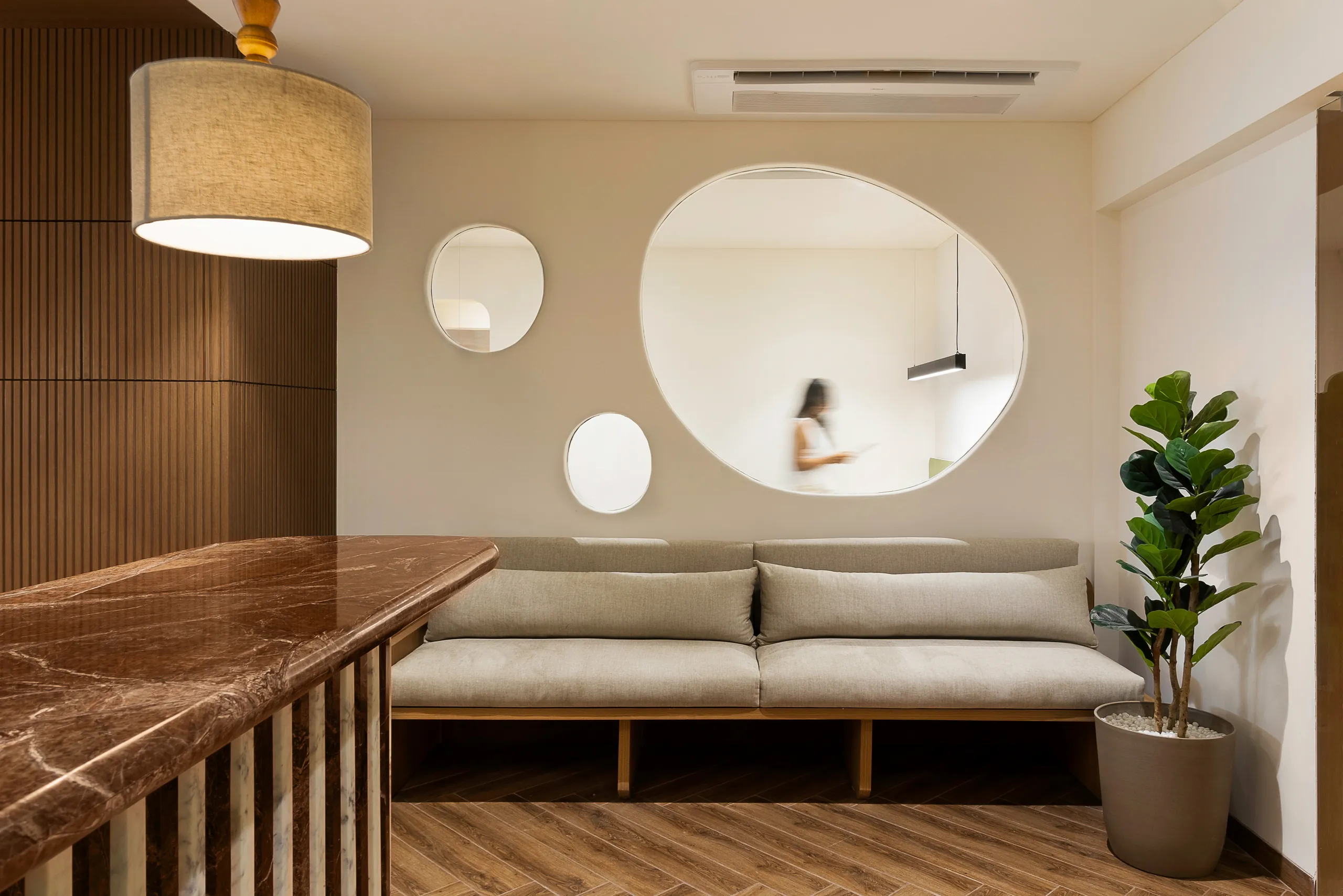 Into the Bend reception lounge with a fluted brown marble counter, sofa and organic mirror cut-outs