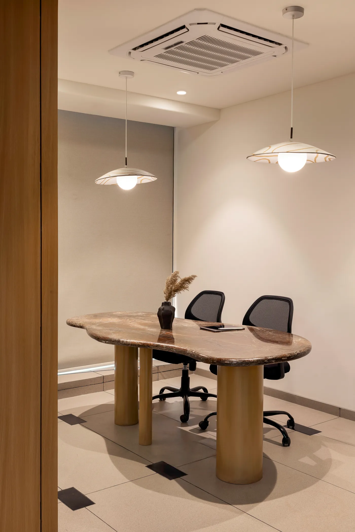 Into the Bend meeting room with an oval marble table on timber legs under two pendant lamps