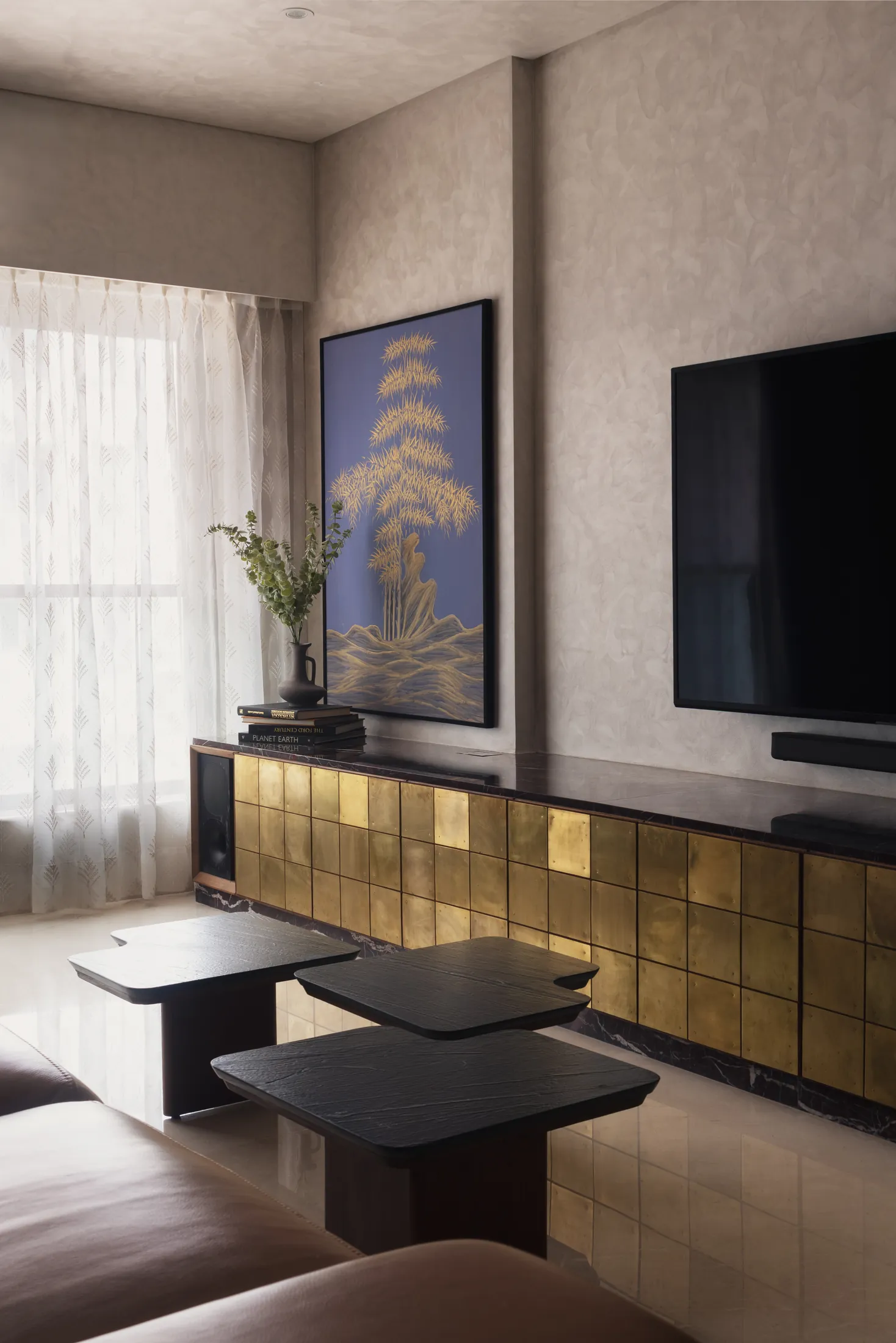 Plum House living room with a brass TV console, nesting coffee tables and a framed botanical artwork