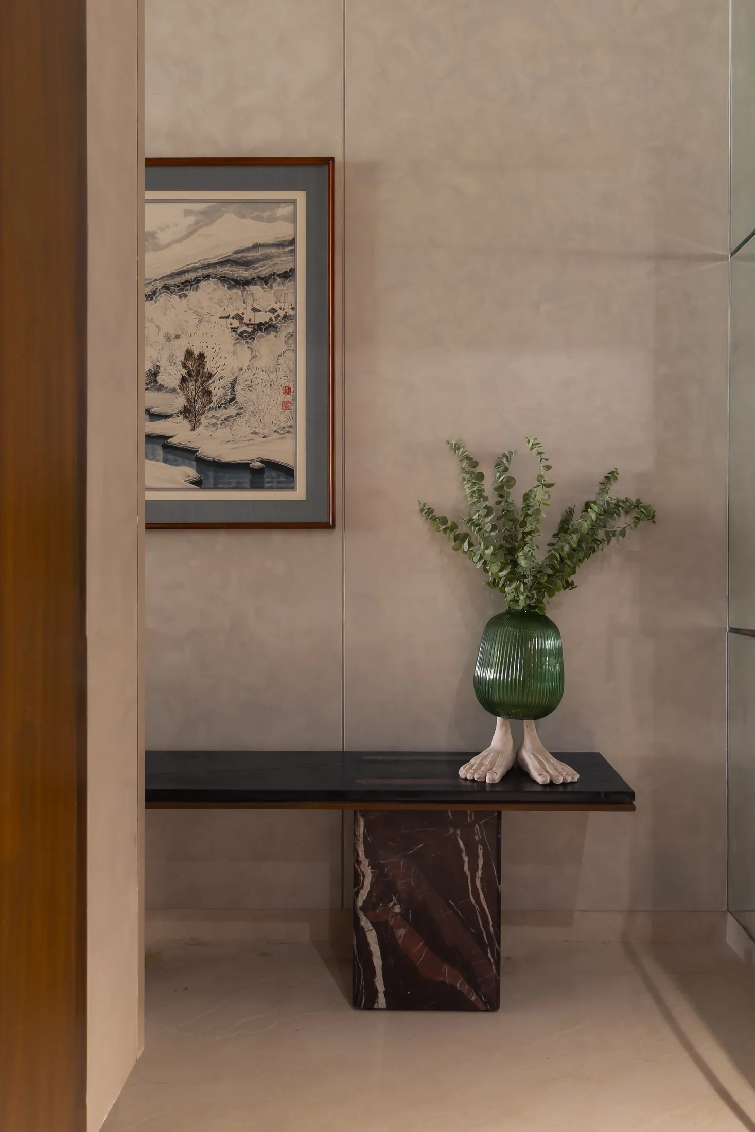 Plum House entrance console with a black marble top, framed print, plant and green glass vase