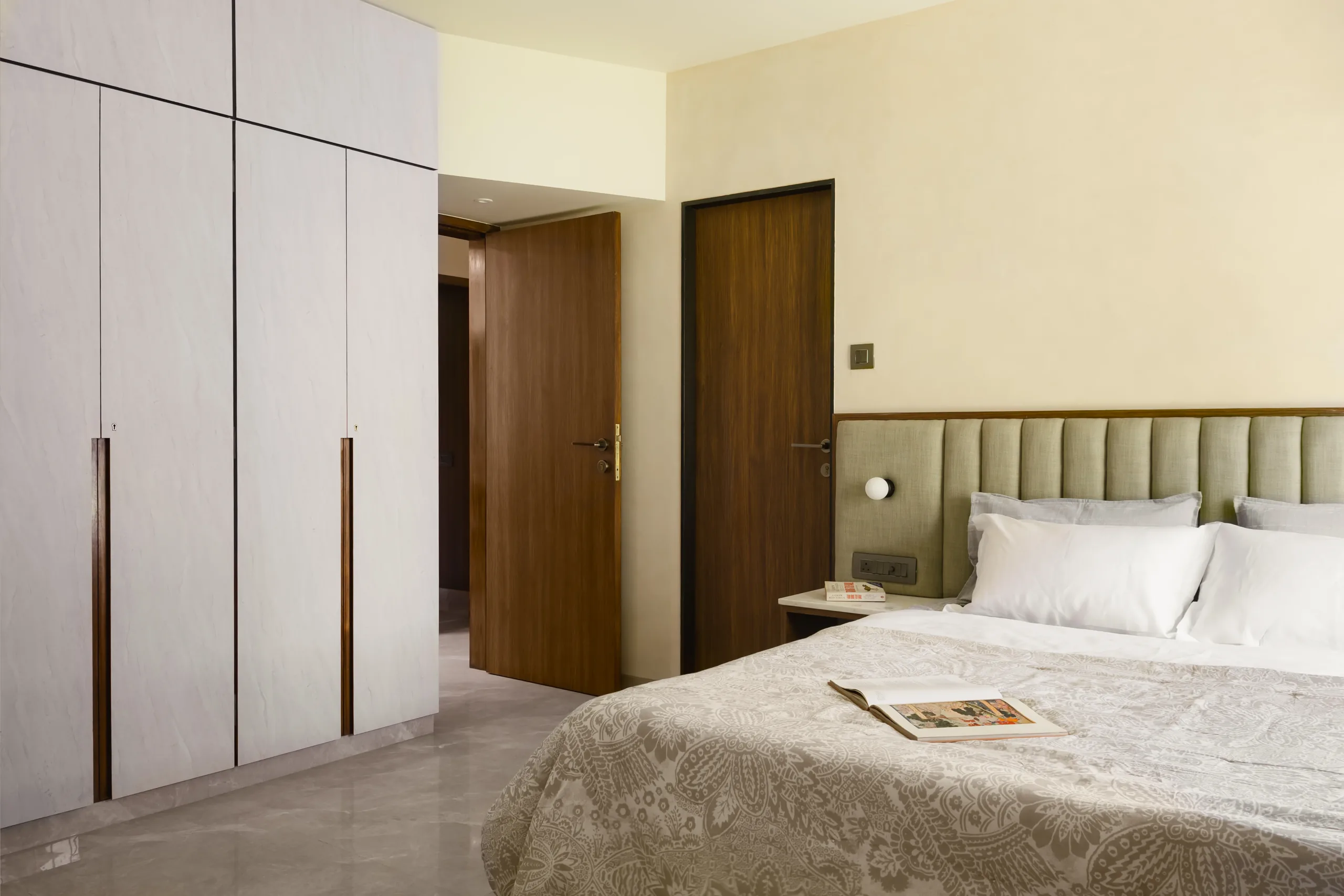 The Nest bedroom with an upholstered bed and full-height wardrobes with timber pulls