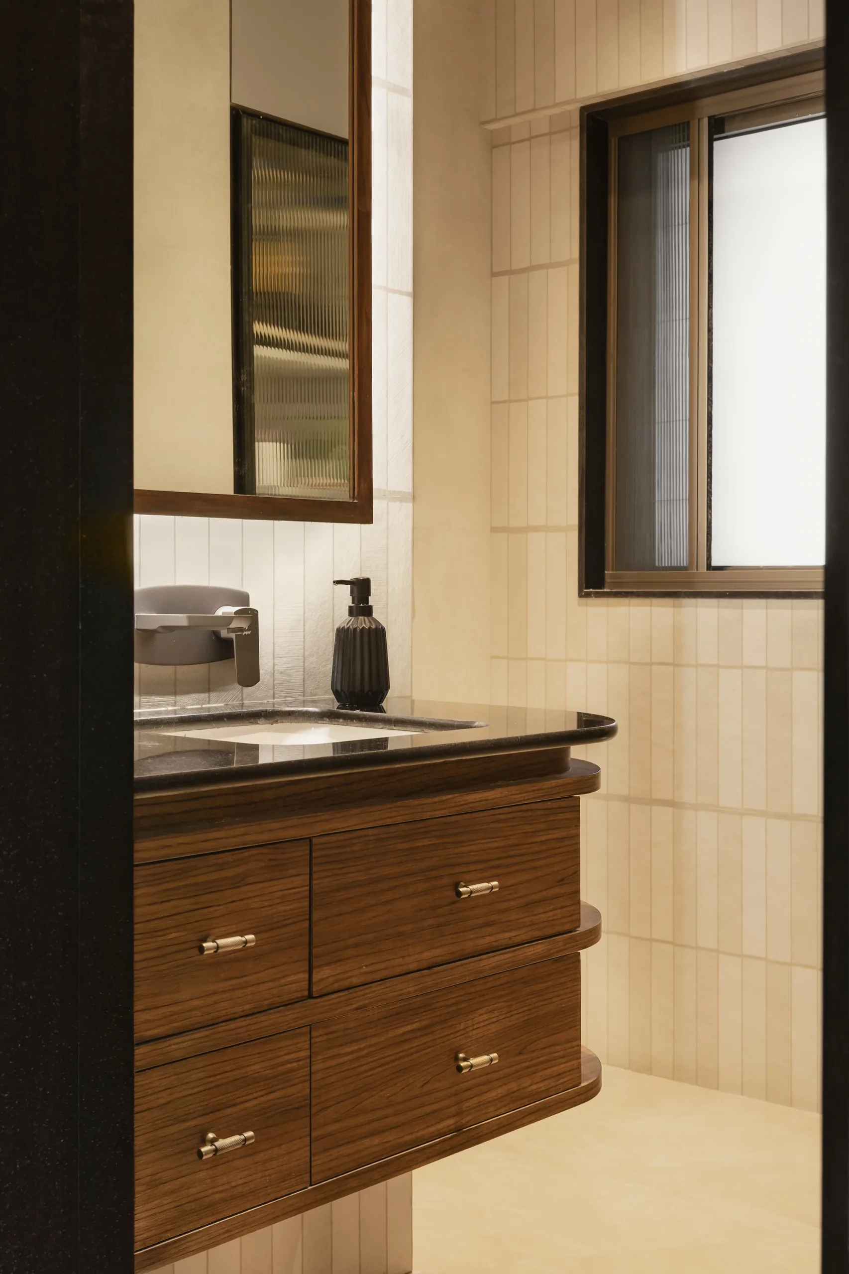 The Nest bathroom with a timber vanity with drawers, black counter, cream tiles and a window