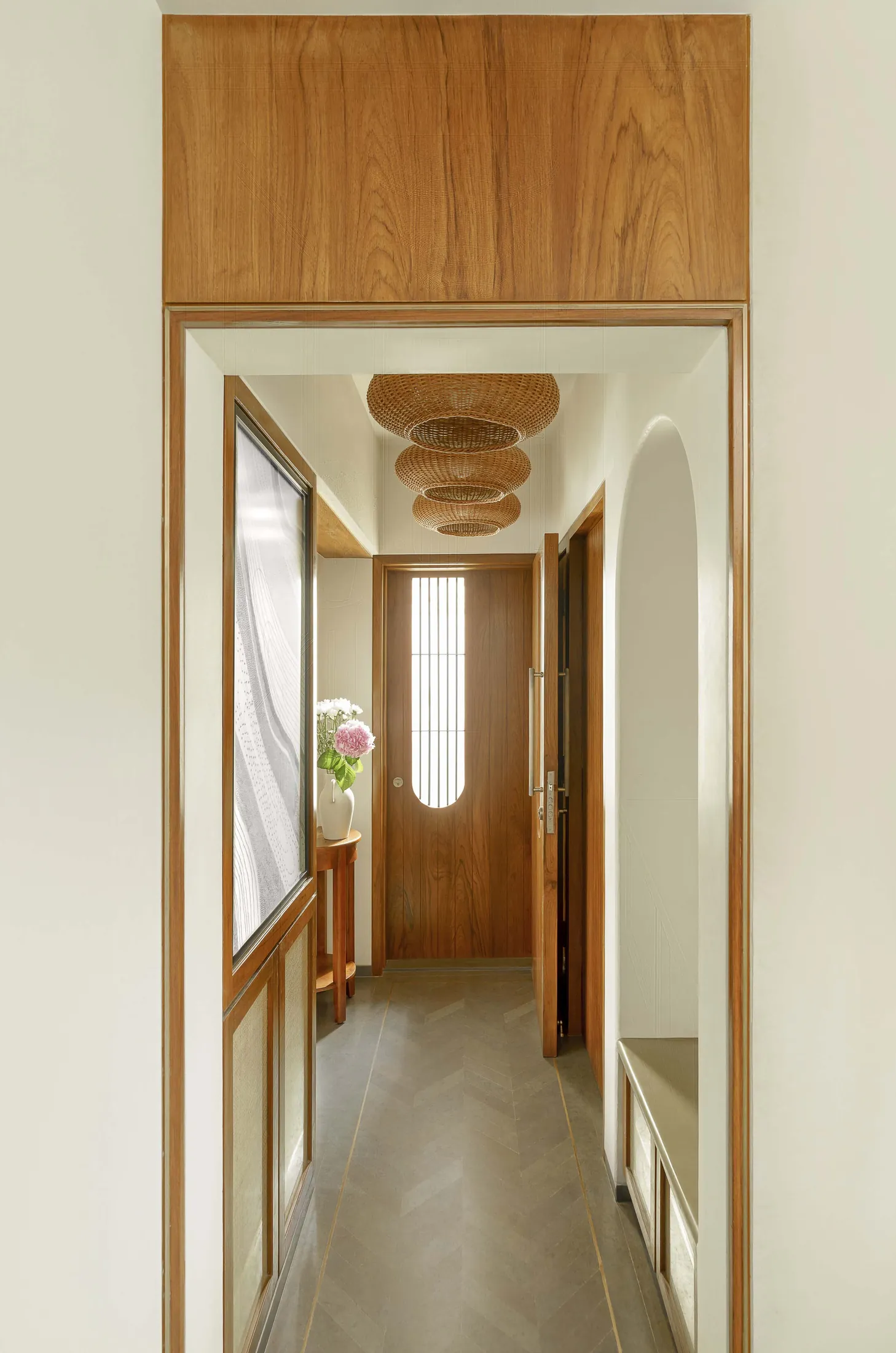 The Seed entrance passage with arched teak frames, rattan pendant lights and a window at the end