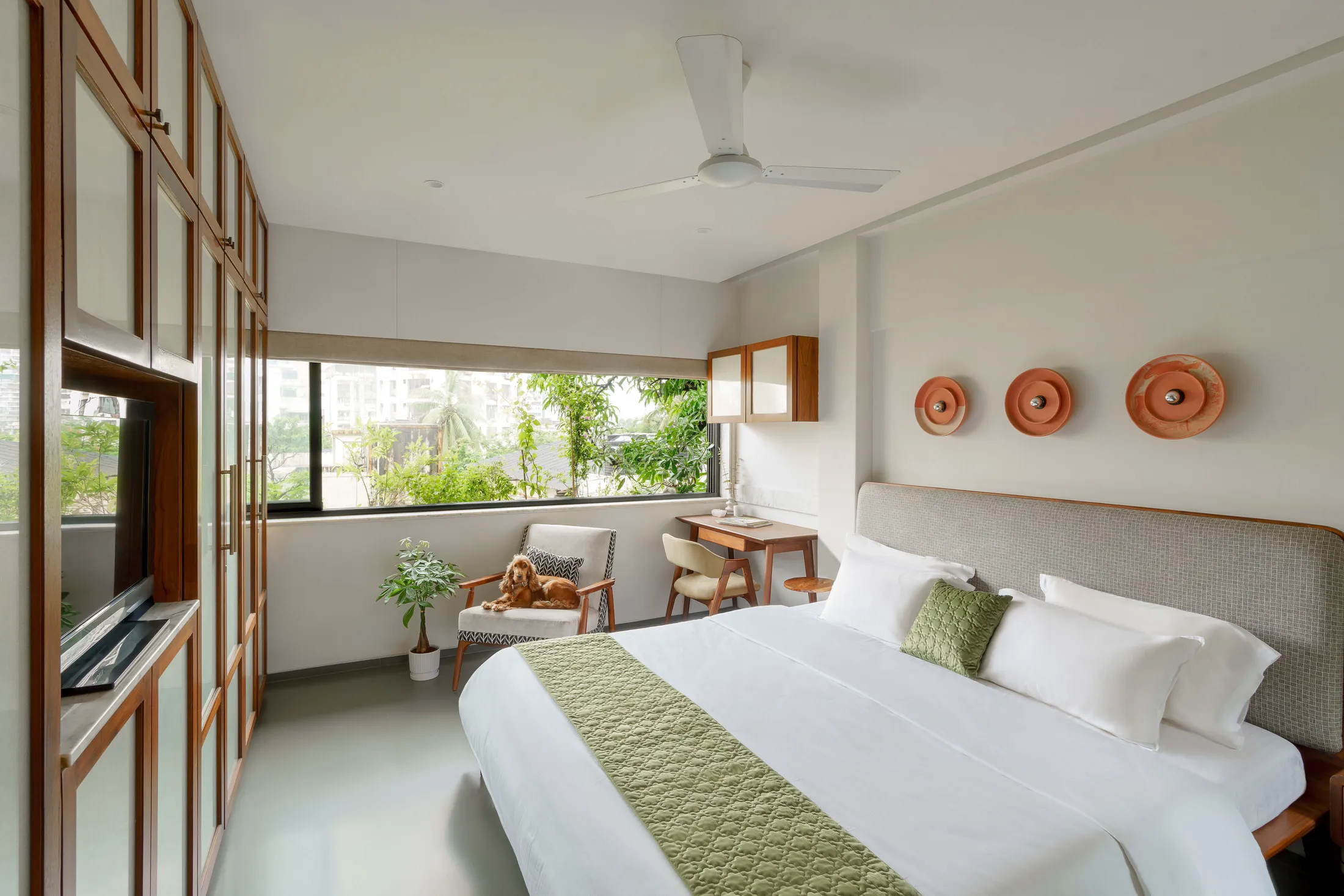 The Seed bedroom with a teak bed, green runner, terracotta wall plates and a window seat